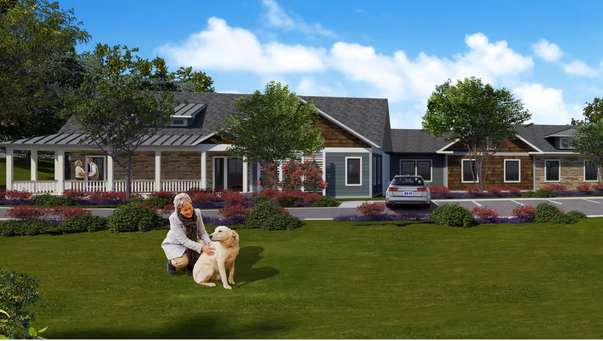 Elderly woman strokes a dog on a grassy lawn in front of Madison at The Range.