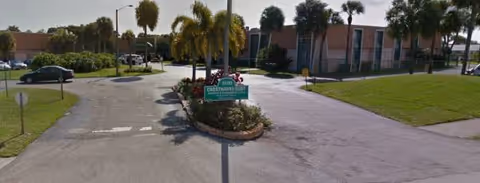 Cresthaven Senior Living Community entrance with drive, landscaping, and sign along a sunny road.