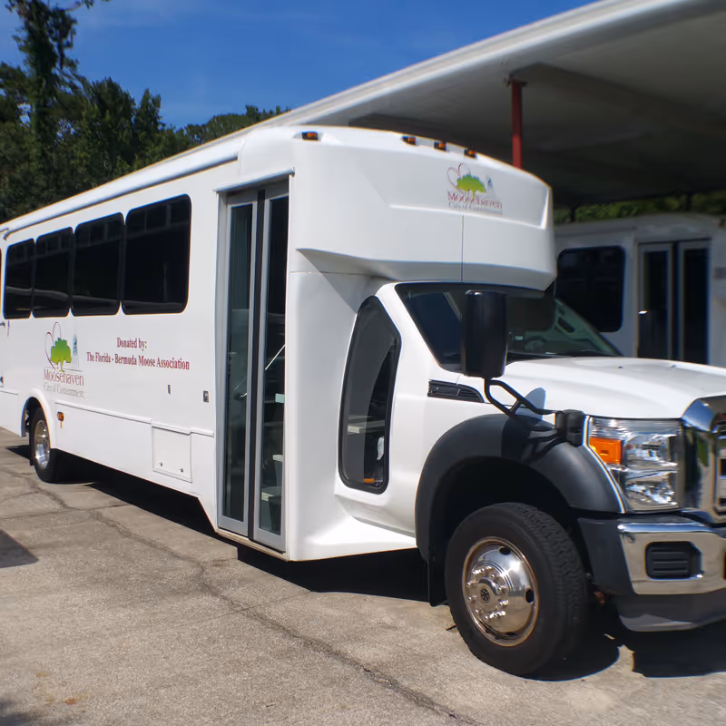 White Moosehaven shuttle bus parked under a canopy outside a building.