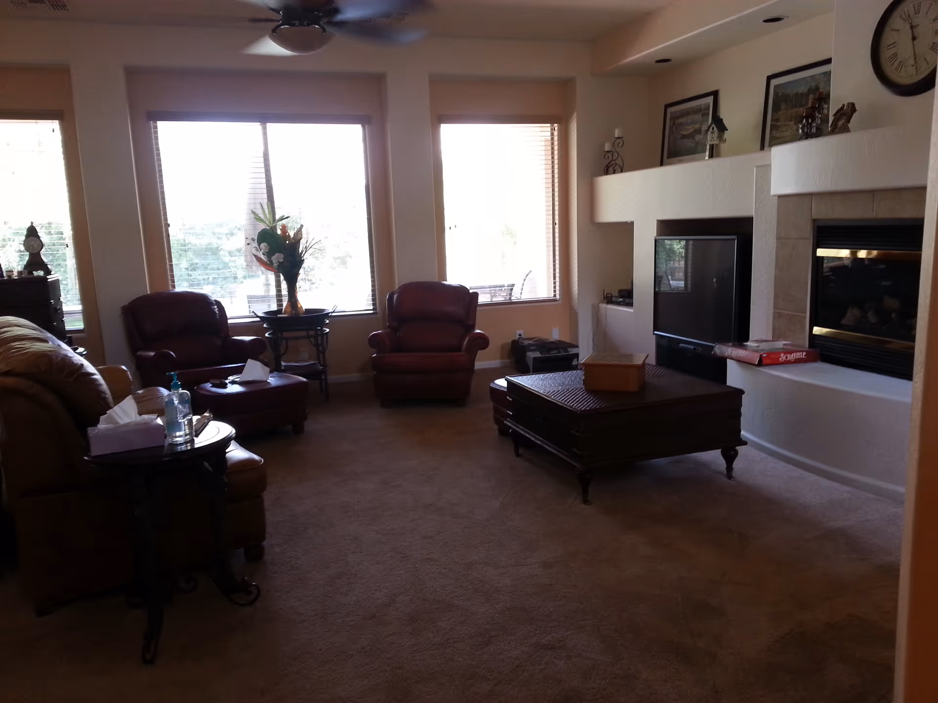 Bright living room with leather seating, a central coffee table, fireplace, TV, and large windows.