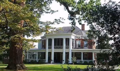 Sunny exterior of Chastain Home for Gentlewomen, a white two-story mansion with columns.