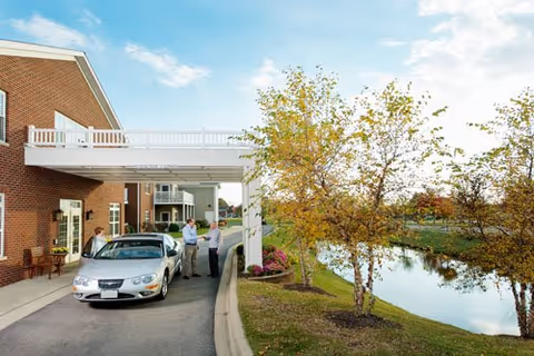 Exterior view of The Keystones of Cedar Rapids with brick building, car under awning, and trees
