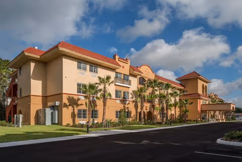 Exterior view of Seasons Largo senior living facility with palm trees.