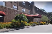 Exterior view of Salem Hills Rehabilitation and Healthcare showing brick building, red canopies, and landscaped entrance.