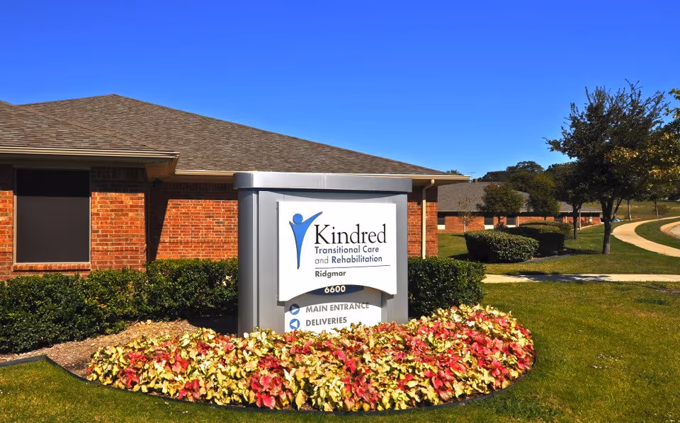 Exterior view of Ridgmar Medical Lodge with a Kindred sign and landscaped bed.