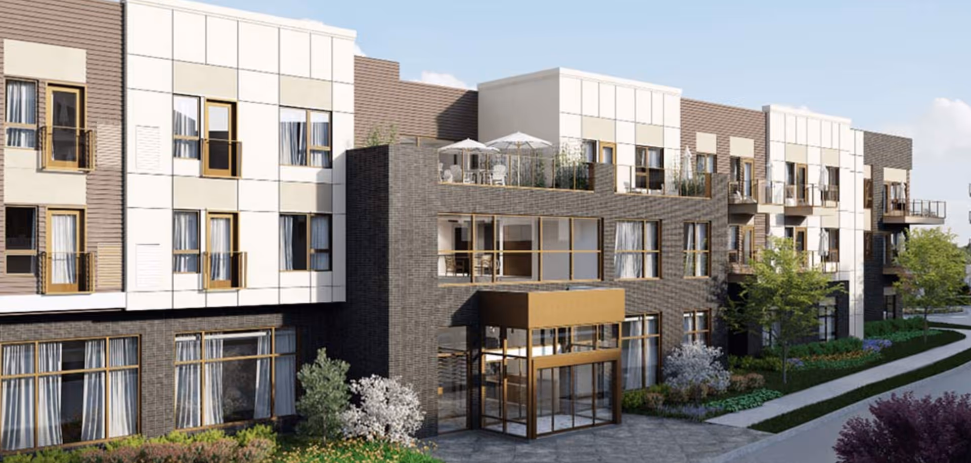 Exterior front view of a modern multi-story senior living building with balconies, large windows, landscaping, and a glass entryway.
