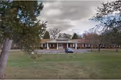 Front view of a single-story senior living facility with parking and lawn.