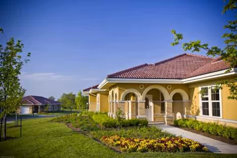 Exterior view of Health Services Center at Santa Marta with yellow walls, arches, and landscaped grounds.