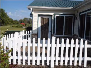 White picket fence fronts a beige senior living home exterior.
