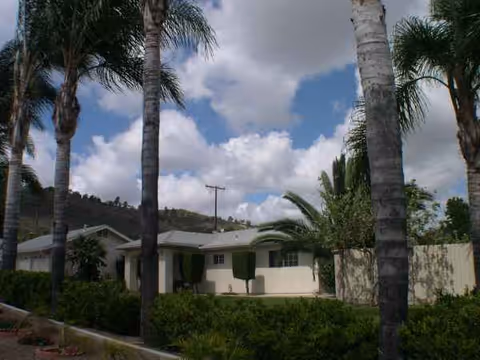 Sunny exterior view of Woodland Borden Care facility with palm trees.