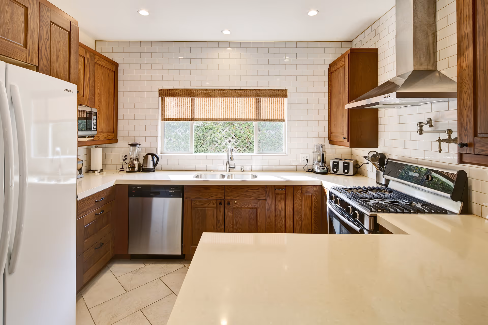 Modern kitchen with wooden cabinets, white countertops, stainless appliances, and a window above the sink