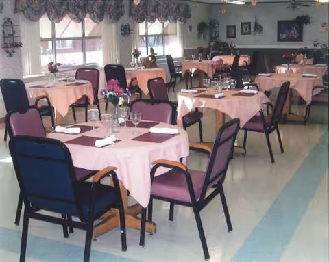 Dining room at Medicalodges Frontenac with pink tablecloths and set tables.