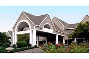 Exterior view of The Nottingham senior living facility with arched entrance and landscaping.
