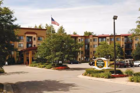 Front view of Pine Ridge Villas of Shelby, a multi-story senior living facility with flag.