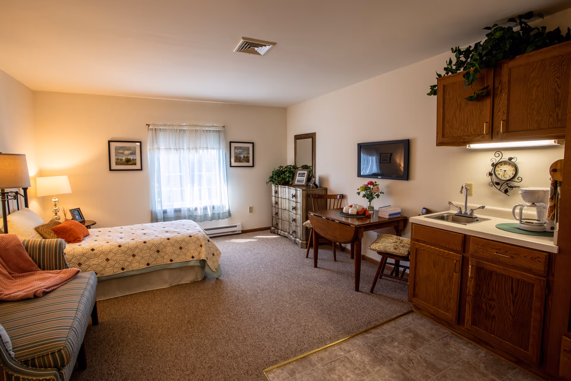 Bright studio apartment with a bed, seating area, small dining table, and a kitchenette.