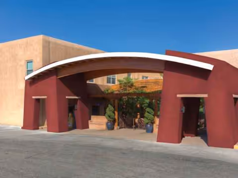 Curved white arch frames a maroon entrance of a southwestern-style senior living facility.