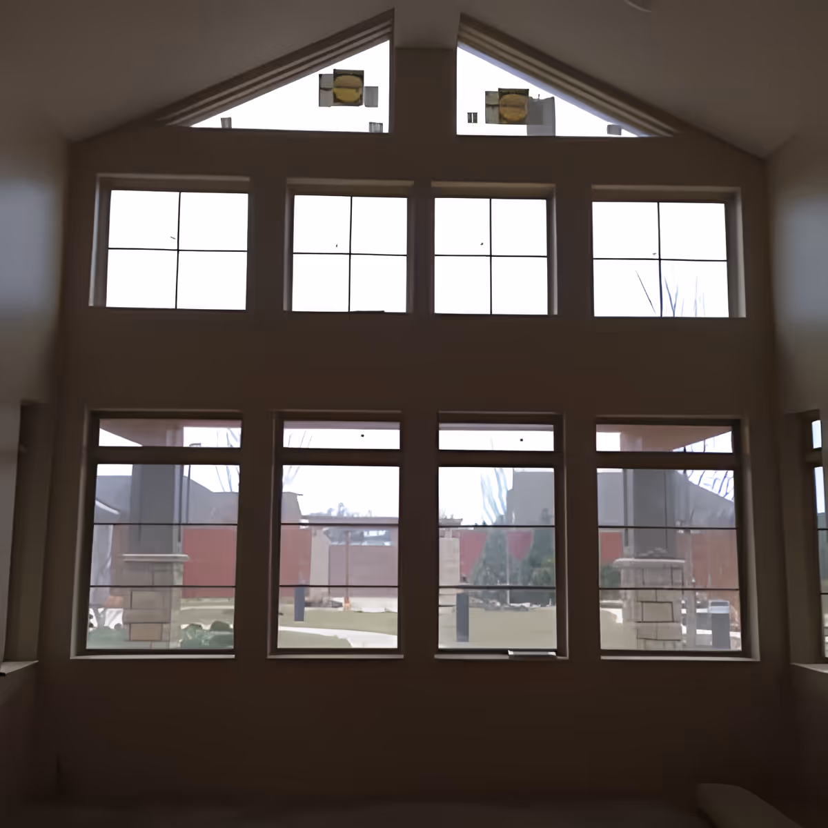 Interior room with a vaulted ceiling and a wall of tall multi-pane windows looking out to an exterior courtyard.