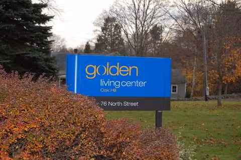 Blue sign for Golden Living Center Oak Hill on a grassy autumn lawn.