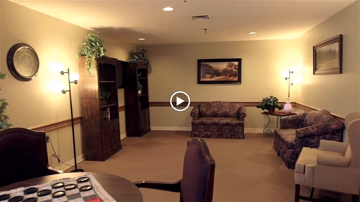 Communal living room with patterned sofas, armchairs, bookshelves, side tables and floor lamps.