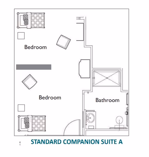 Floor plan layout of a standard companion suite labeled 'Standard Companion Suite A' showing two bedrooms each with a bed and chair, and a shared bathroom with a sink, toilet, and shower.
