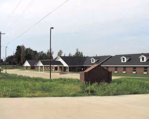 Brick senior living campus with a front entry and surrounding lawn.