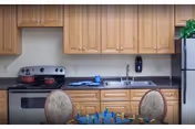 A compact kitchen area with wooden cabinets, stove, sink, and a small table.
