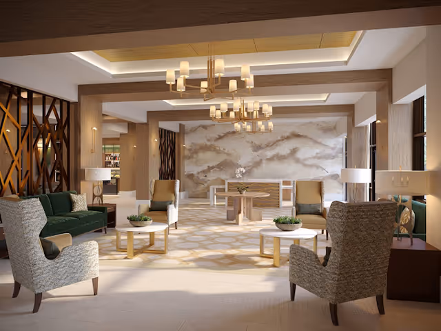 A spacious and elegant senior living facility common area with comfortable armchairs and sofas arranged around small round tables with decorative plants. The room features modern chandeliers, wooden beams on the ceiling, and a large abstract wall art piece. Large windows allow natural light to fill the space.