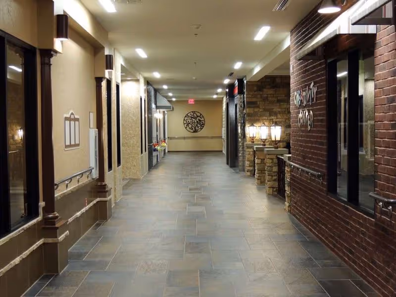 Well-lit interior hallway with tiled floor, handrails, decorative columns and an Activity Center sign on the right.
