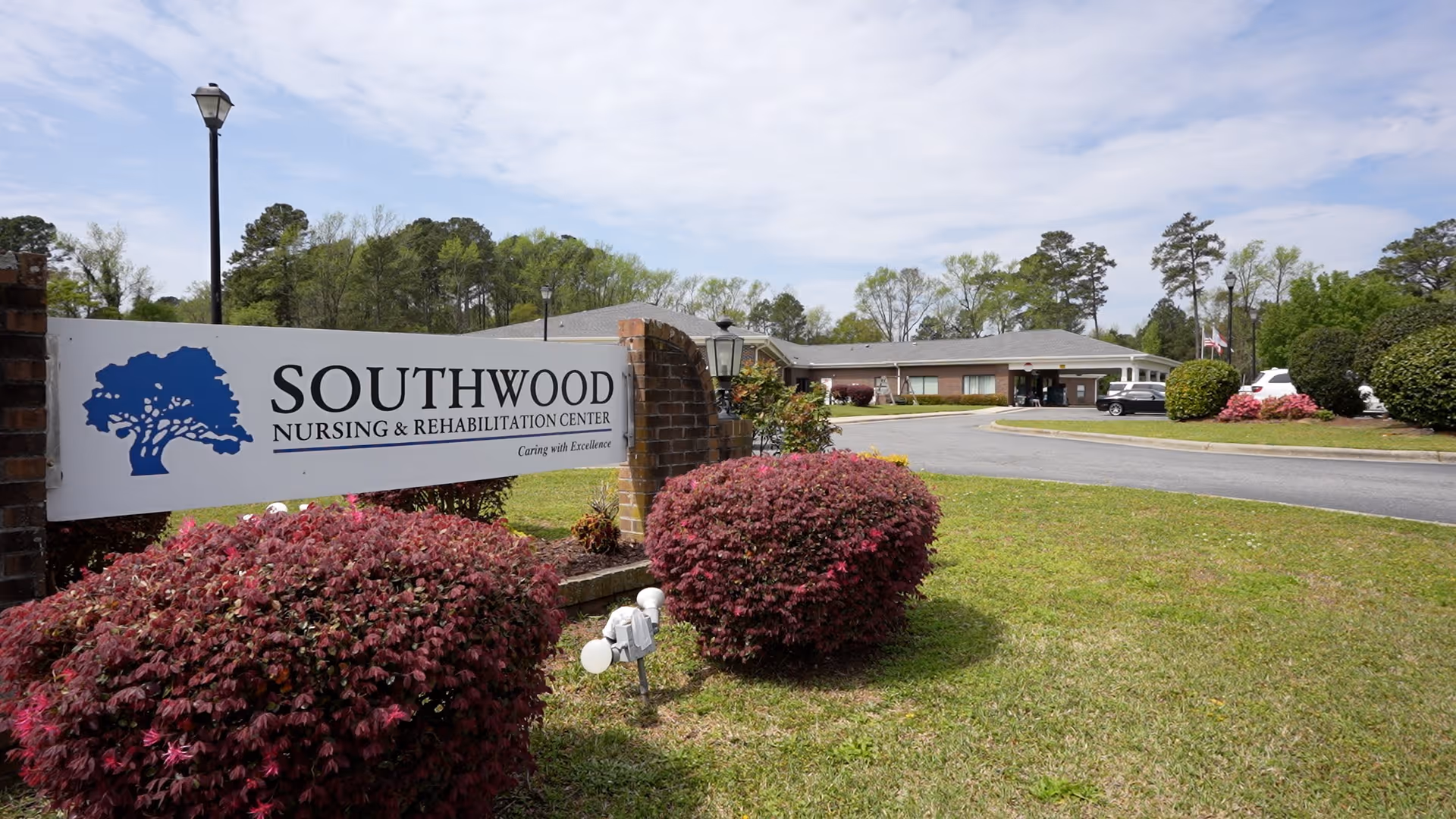 Front entrance and sign for Southwood Nursing & Rehabilitation Center with landscaped bushes and a circular driveway.