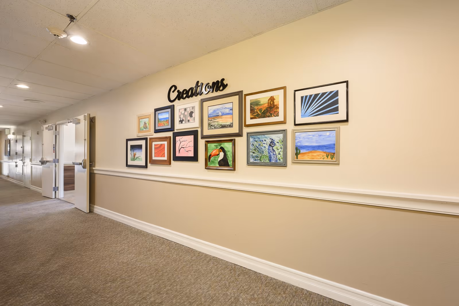 Well-lit interior hallway with framed artwork labeled "Creations" along the wall and open double doors at the end.