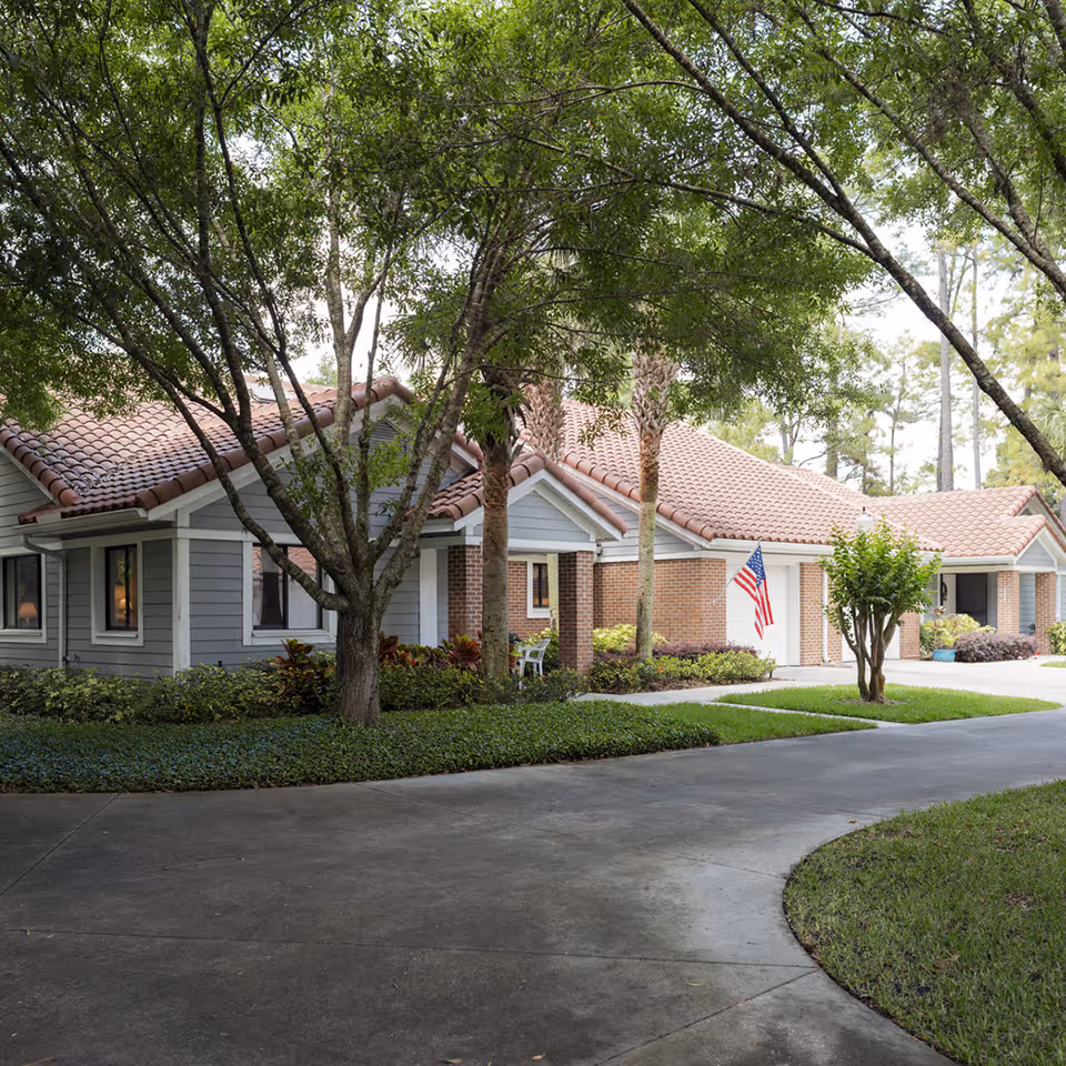 Single-story building with a tiled roof, trees and landscaping along a curved driveway and an American flag by the entrance.
