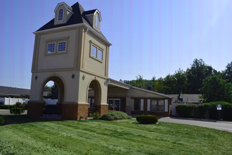 Front view of a senior living facility with a tower entrance and lawn