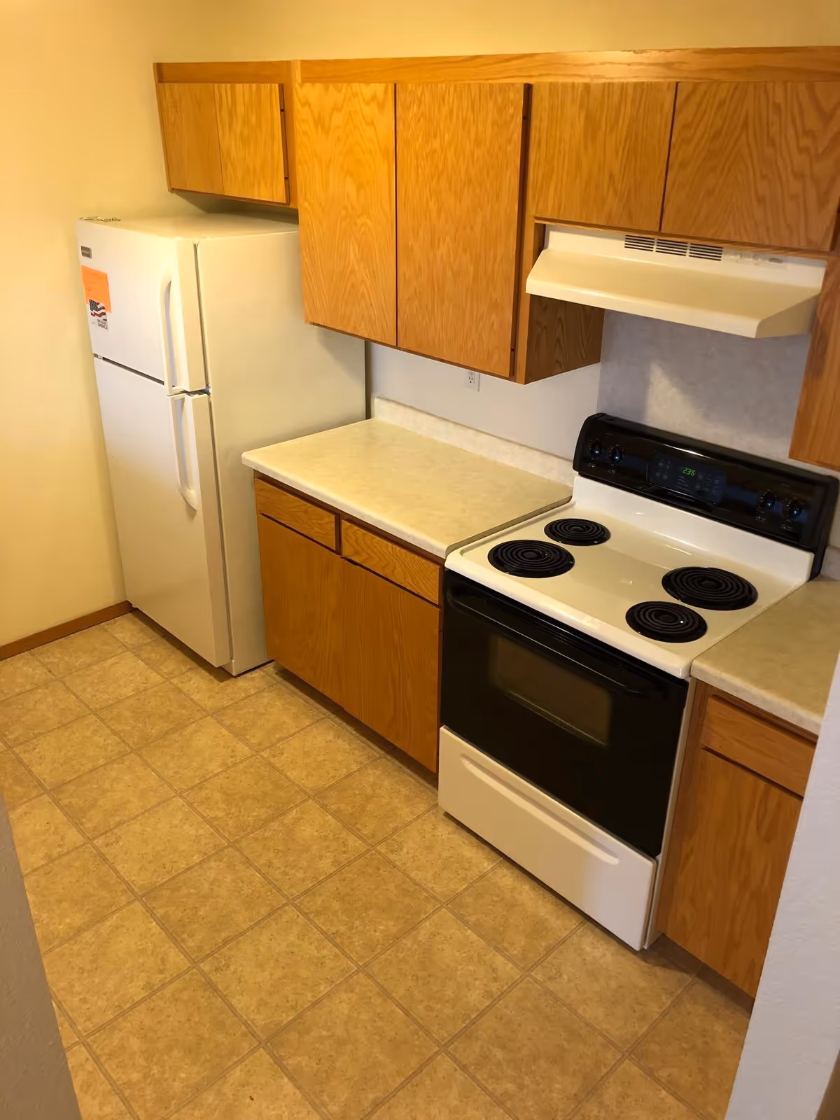 Small kitchen with oak cabinets, a white refrigerator, electric stove, and laminate countertops.