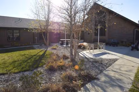 Exterior view of Linn Community Nursing Home with courtyard seating and trees.