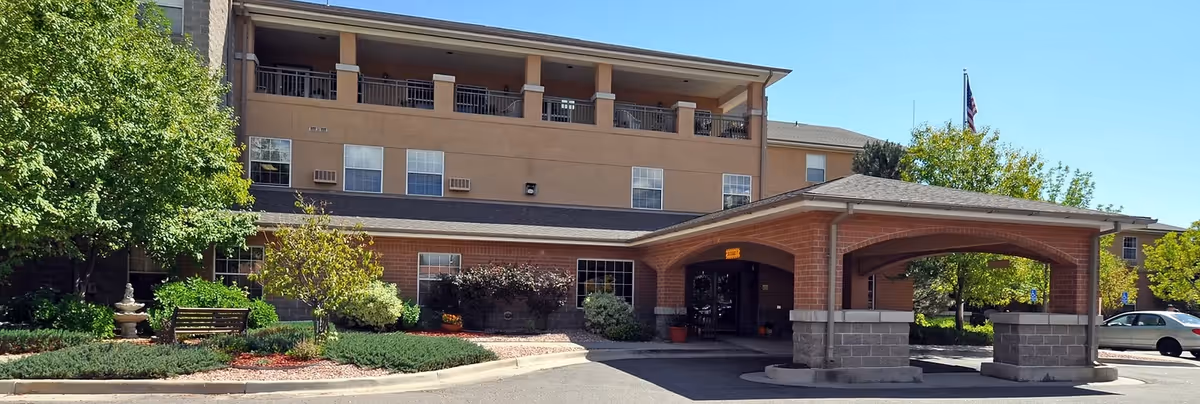 Front entrance of Libby Bortz Assisted Living with a covered porte-cochère, landscaped beds, and upper-level balconies.