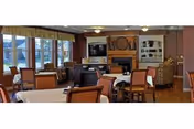 Dining area with multiple tables and chairs, a fireplace and TV, and large windows.