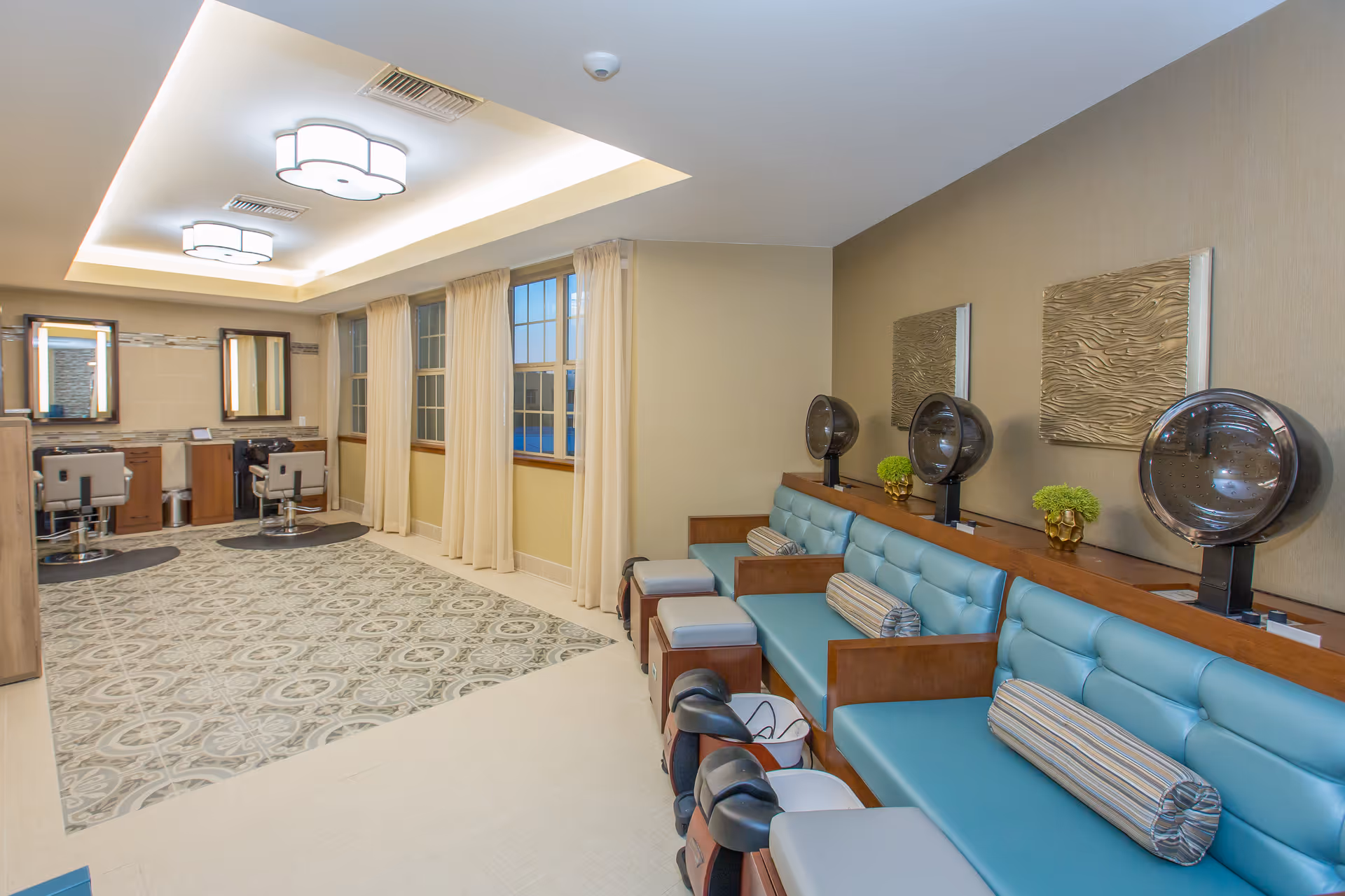 Bright salon-style interior with teal bench seating, hooded hair dryers and styling stations near windows.