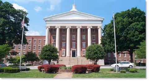 Front view of a neoclassical building with columns and trees.