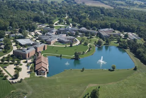 Aerial view of Copeland Oaks campus with multiple buildings surrounding a pond with fountains and landscaped lawns.