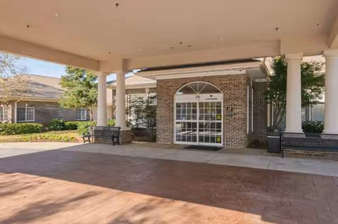 Covered entrance of Life Care Center of Lawrenceville with brick façade and glass doors.