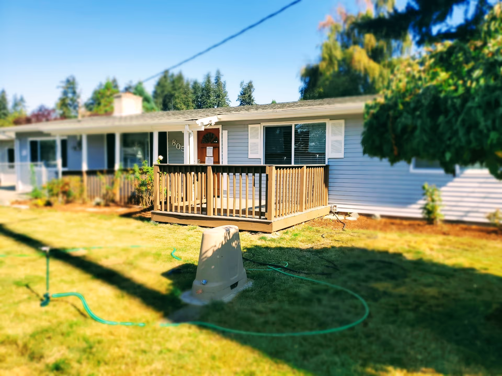 Single-story light blue care home with a small wooden front porch and a grassy yard.