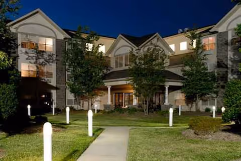 Exterior view of Westchester Manor Nursing Center at dusk, with lit entrance and walkway.