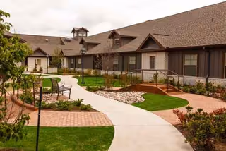 Exterior view of Larkspur senior living courtyard with walkway, landscaping, and benches.