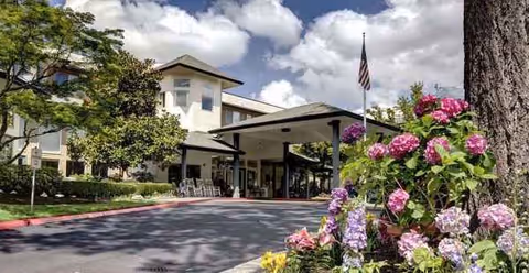 Solista Bellevue senior living facility entrance with covered drop-off and colorful flowers.