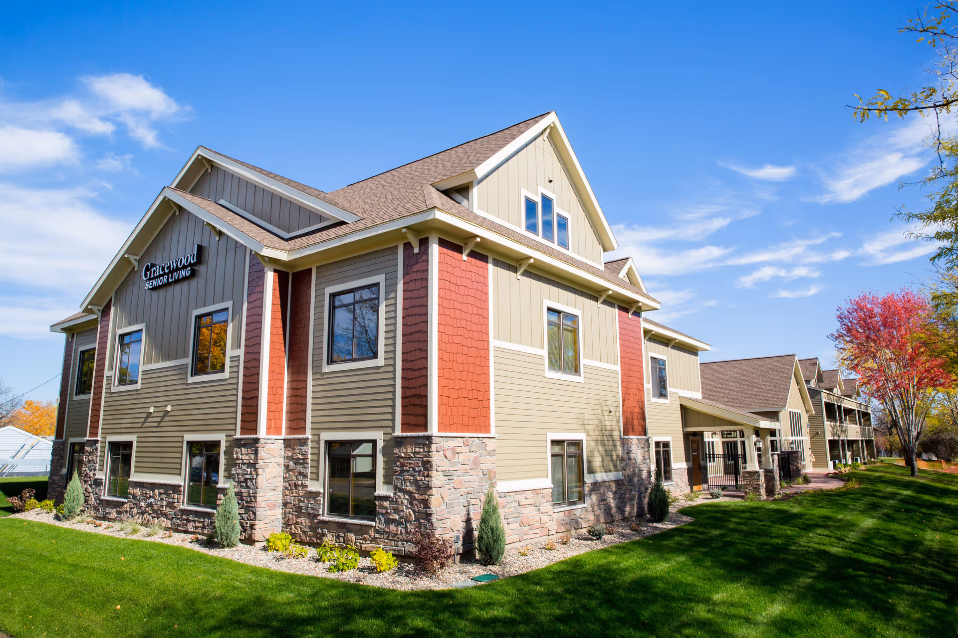 Exterior of the Gracewood senior living building with landscaped lawn under a blue sky.