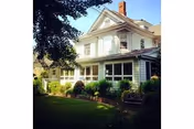 Two-story house with pale siding, white trim, and a landscaped front lawn.