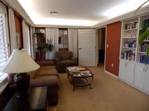 Cozy living room at Heartsworth House with sofa, chairs, coffee table, and bookshelves.