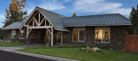 Single-story stone-clad senior living facility with a covered front entrance and manicured lawn.