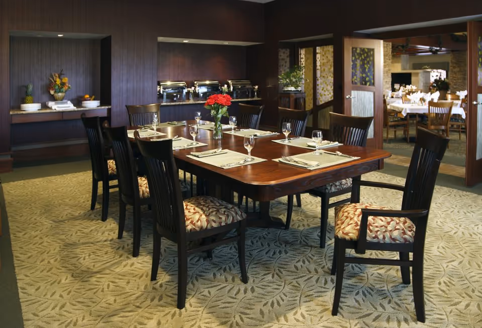 Well-appointed dining room with a large wooden table set for eight, upholstered chairs, and buffet stations along the back wall.