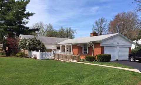 Single-story brick and white-siding senior living facility with ramp and lawn.